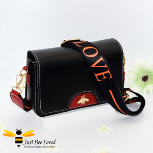 crossbody handbag in black and wine red, featuring a gold bee embellishment, wide matching canvas strap with 'LOVE' text. 