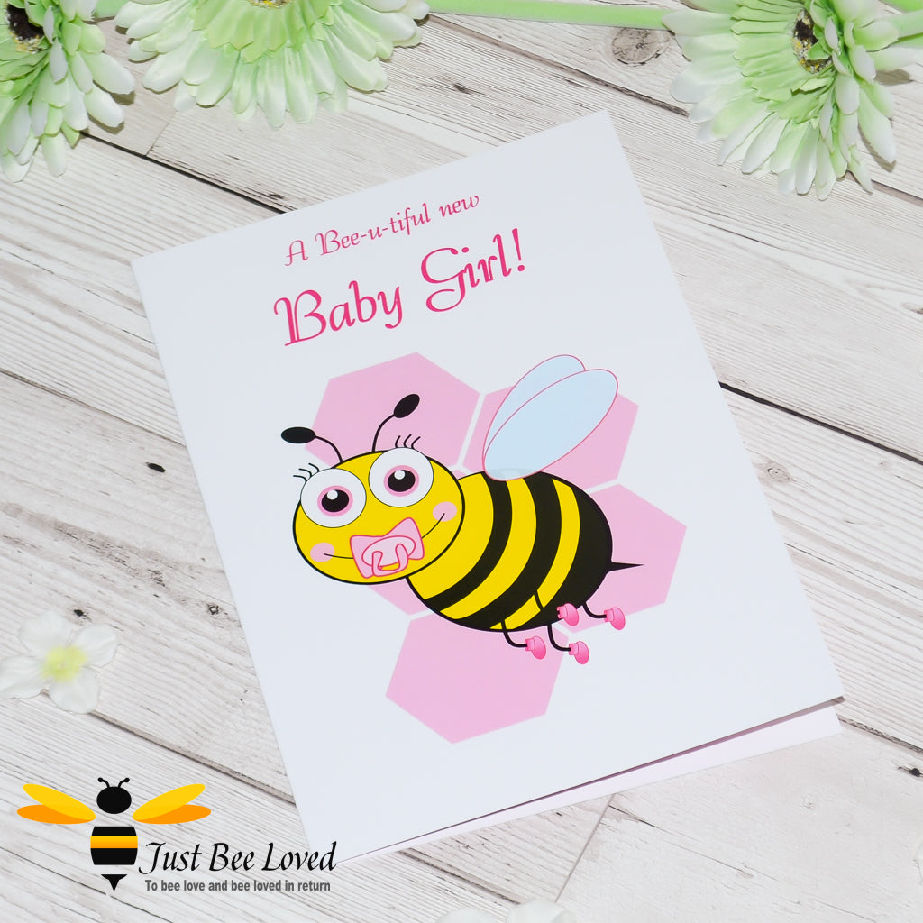 Just Bee Loved Little Bee New Baby Girl Greeting Card featuring a cute baby bumble bee with a dummy design by Artist Yasmin Flemming