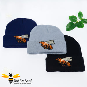Ribbed knit beanie skull caps featuring a large front embroidered bee motif in blue, grey and black colours.