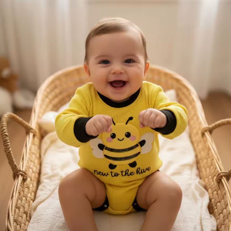 Baby boy wearing a yellow bee themed romper bodysuit with an embroidered bee and 'new to the hive' text.