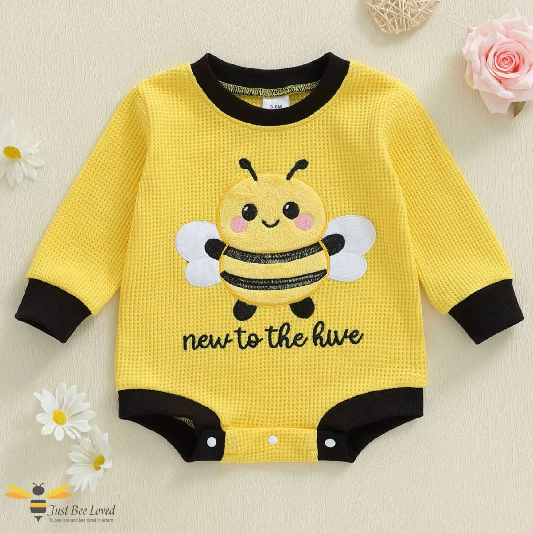Yellow baby romper bodysuit with an embroidery bee design and text 'new to the hive'.