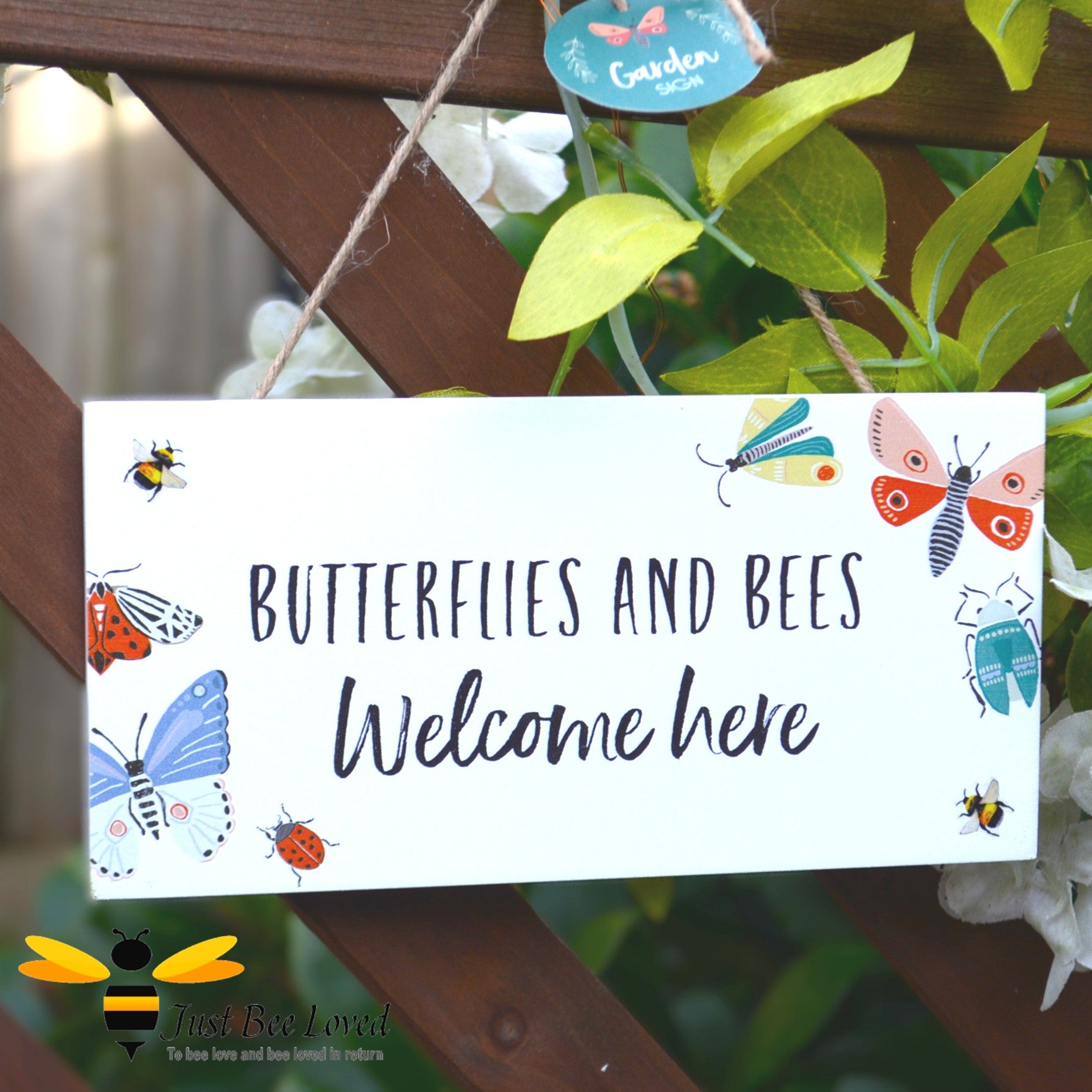 A wooden hanging garden sign with the text 'Butterflies and Bees Welcome Here' and decorative butterflies and bees on it.