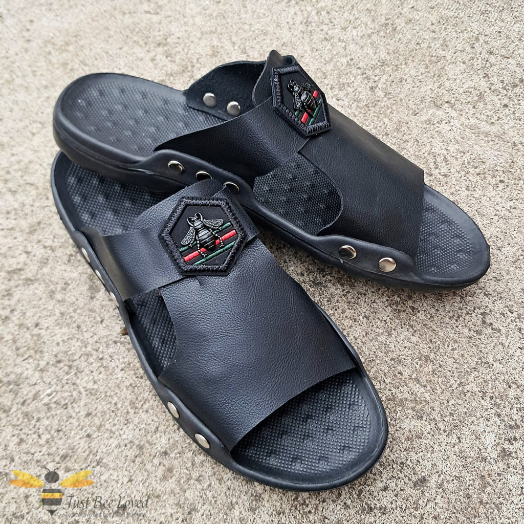 Men's black faux leather slides, indoor slippers with an embroidered hexagon bee motif applique.