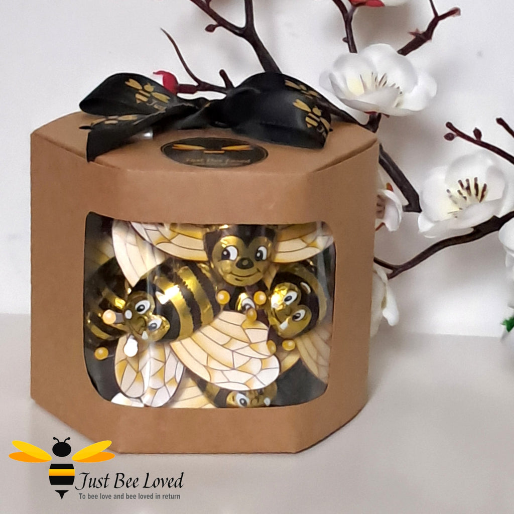 A gift box of milk chocolate novelty bees shaped like bees with a black ribbon on top.