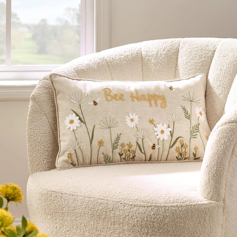 Catherine Lansfield natural colour boudoir cushion featuring embroidered bees, daisies, wildflowers with 'bee happy' message.