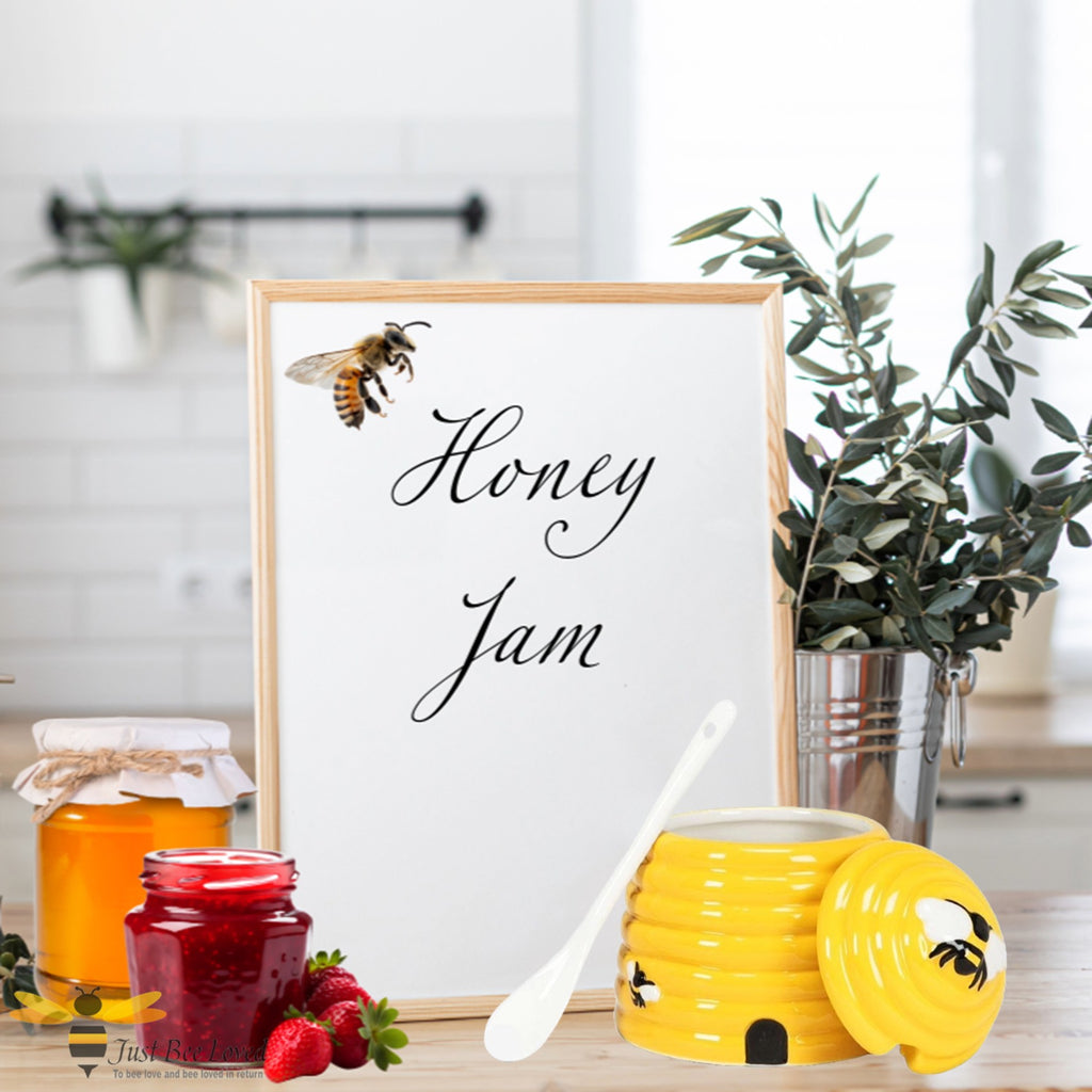 Framed print with a bee and 'Honey Jam' text, surrounded by honey jars, a jar of jam and a yellow hive shaped pot with bee design.