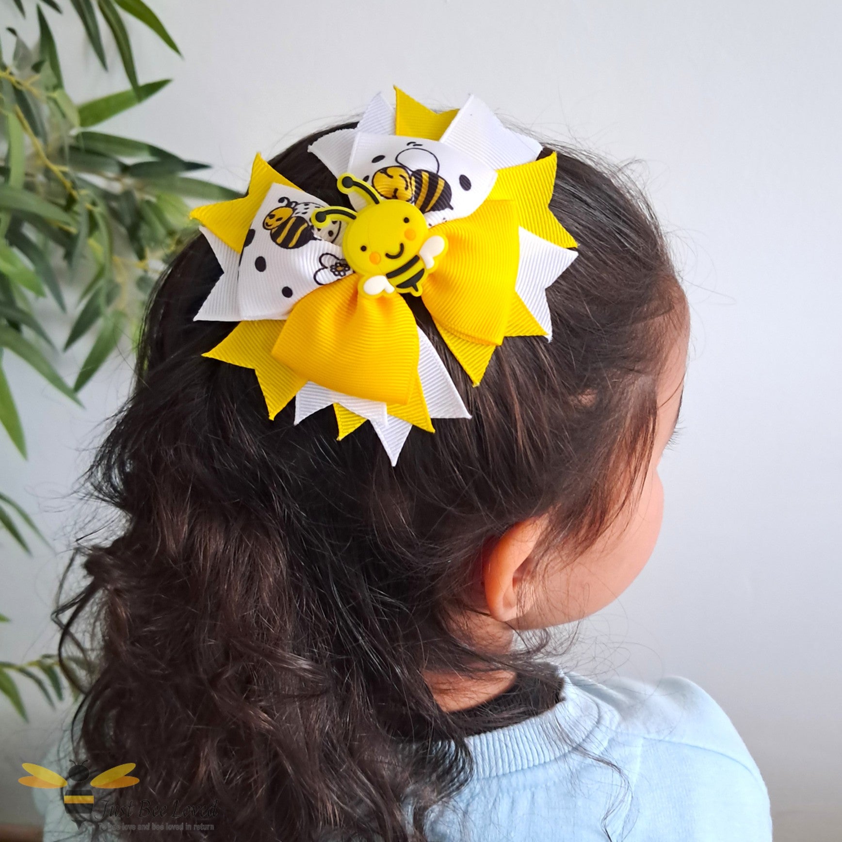 Child with a yellow and white hair bow featuring bee designs.