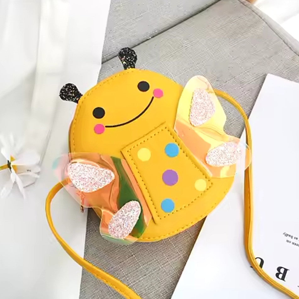 A yellow bee-shaped shoulder bag with embroidered facial features, glittery wings, and a yellow strap.