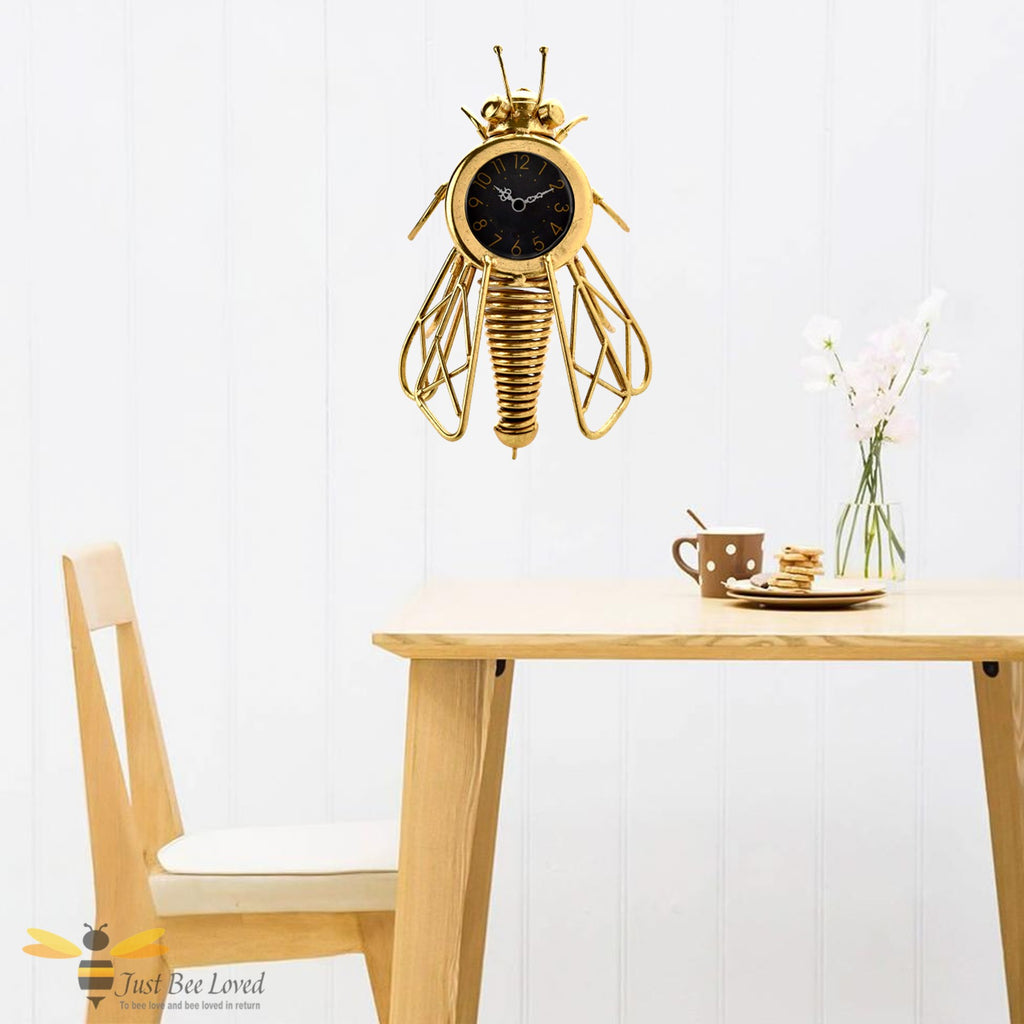 Antique gold effect metal wall clock designed in the shape of a honey bee.