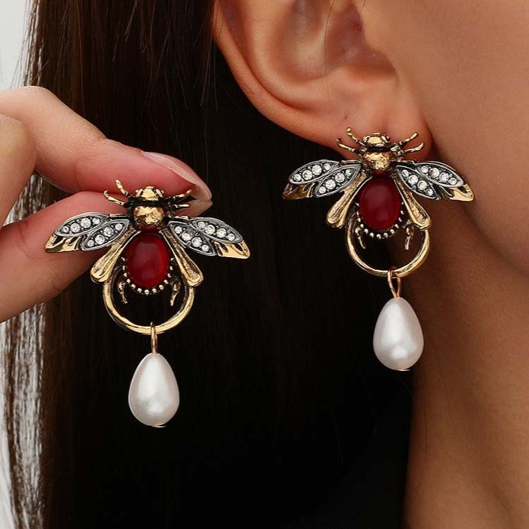 Vintage style bee shaped earrings with a teardop imitation pearl in gold colour.