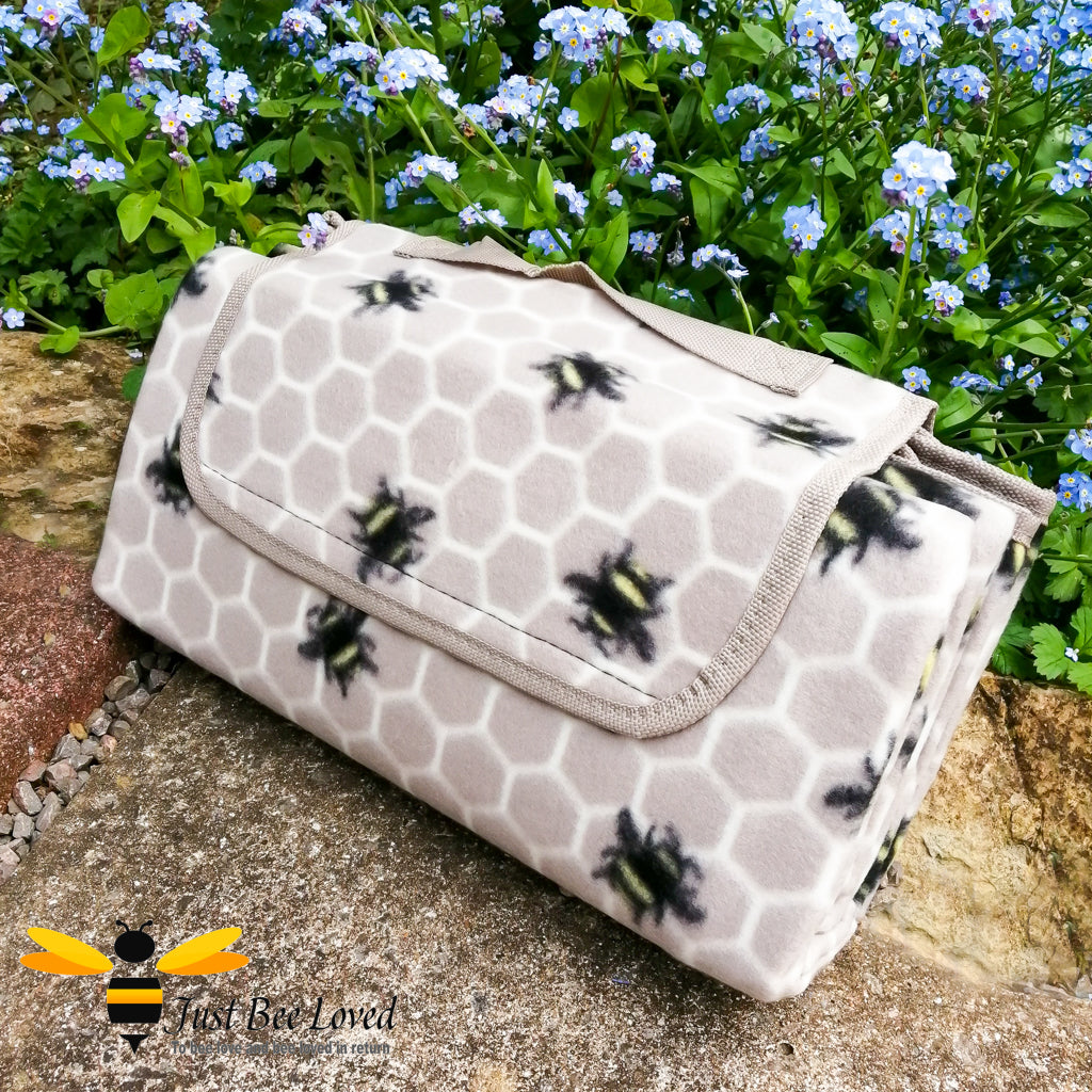 Foldable picnic fleece waterproof blanket with carry handle in taupe colour, with an all over honeycomb and bees print.