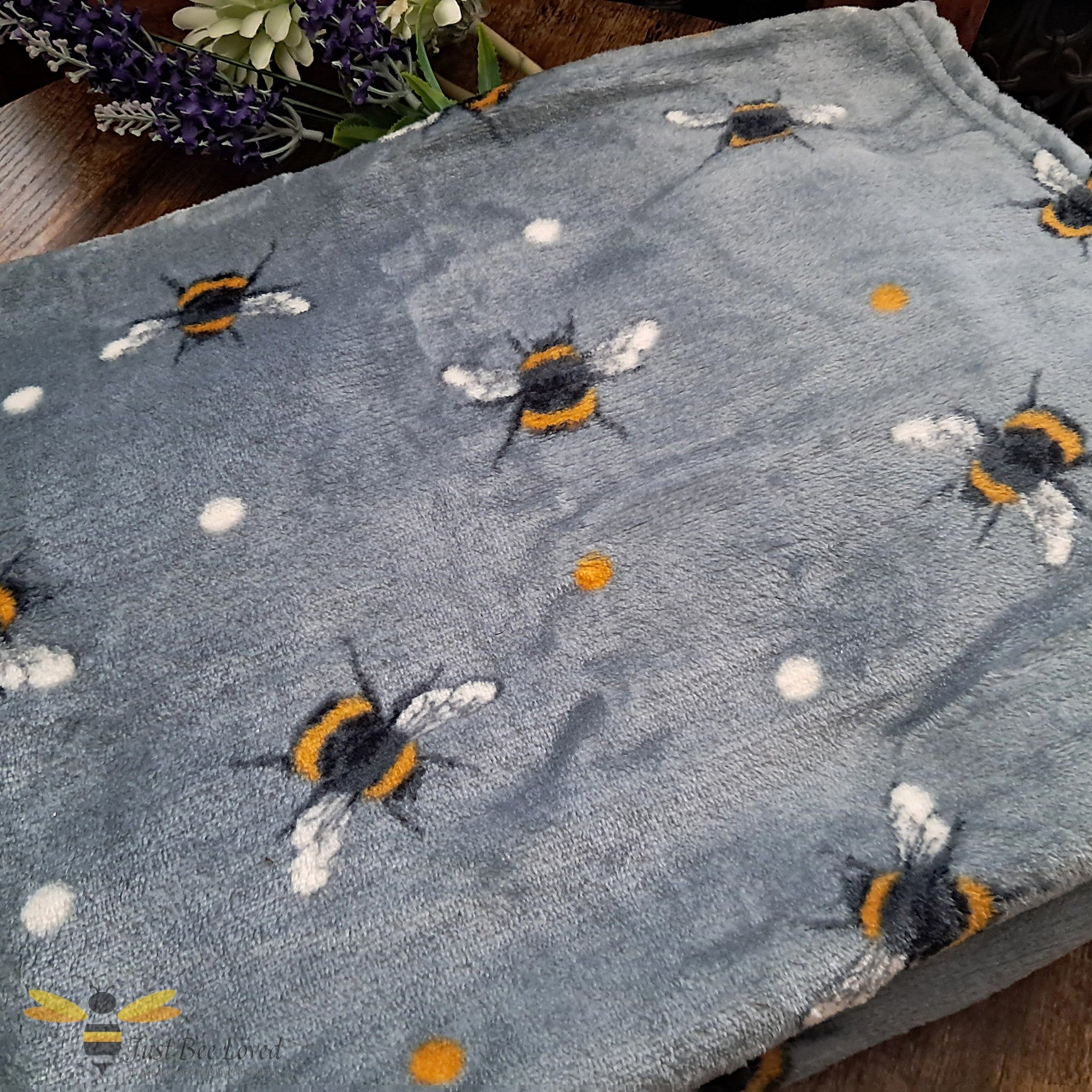 Grey throw blanket with an all over bee pattern.