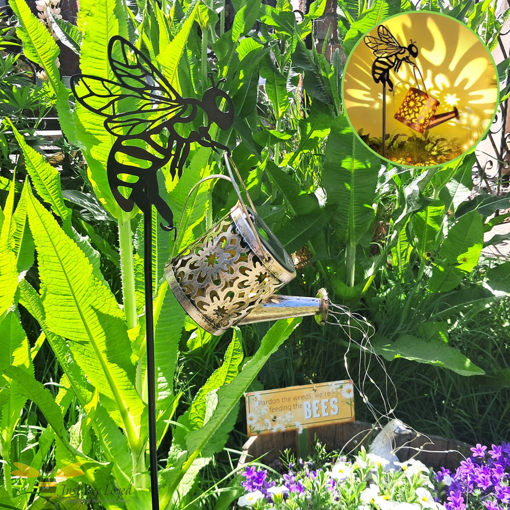 Metal garden stake shaped like a bee with a solar light watering can feature and cascading string lights.