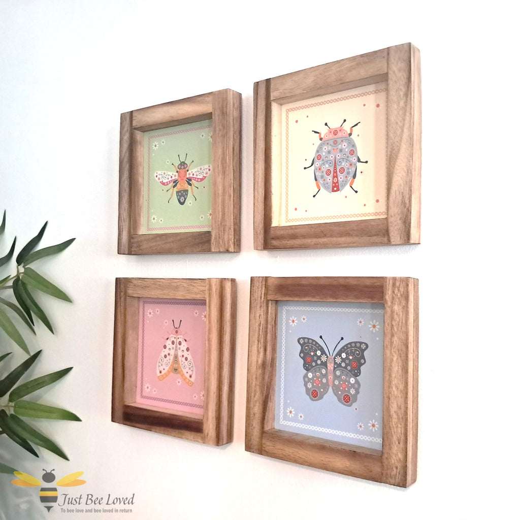 Set of four wooden-framed floral illustrations of a bee, butterfly, ladybird, and a moth.