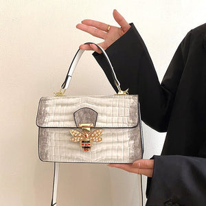 Woman showcasing a White Faux patent pu leather handbag with large gold bee clasp