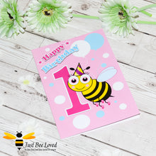 Load image into Gallery viewer, Happy 1st Birthday bee greeting card for girl featuring a cartoon bee with a party hat and balloons on a pink and white background.