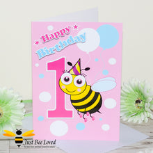 Load image into Gallery viewer, Happy 1st Birthday greeting bee card for girl featuring a cartoon bee with a party hat and balloons with a pink background.