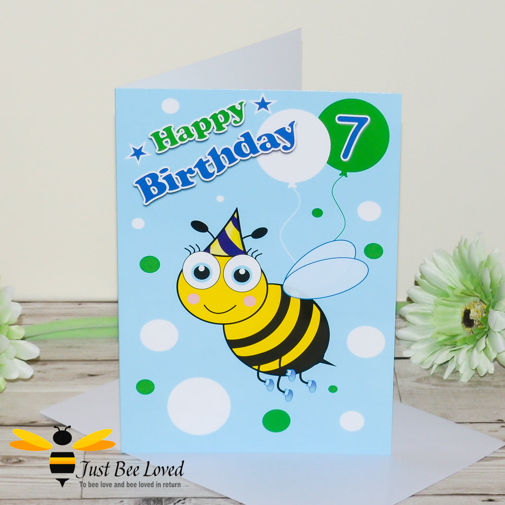 a 7th birthday greeting card for boy featuring a cartoon bee wearing a party hat with colourful balloons and the number 7.
