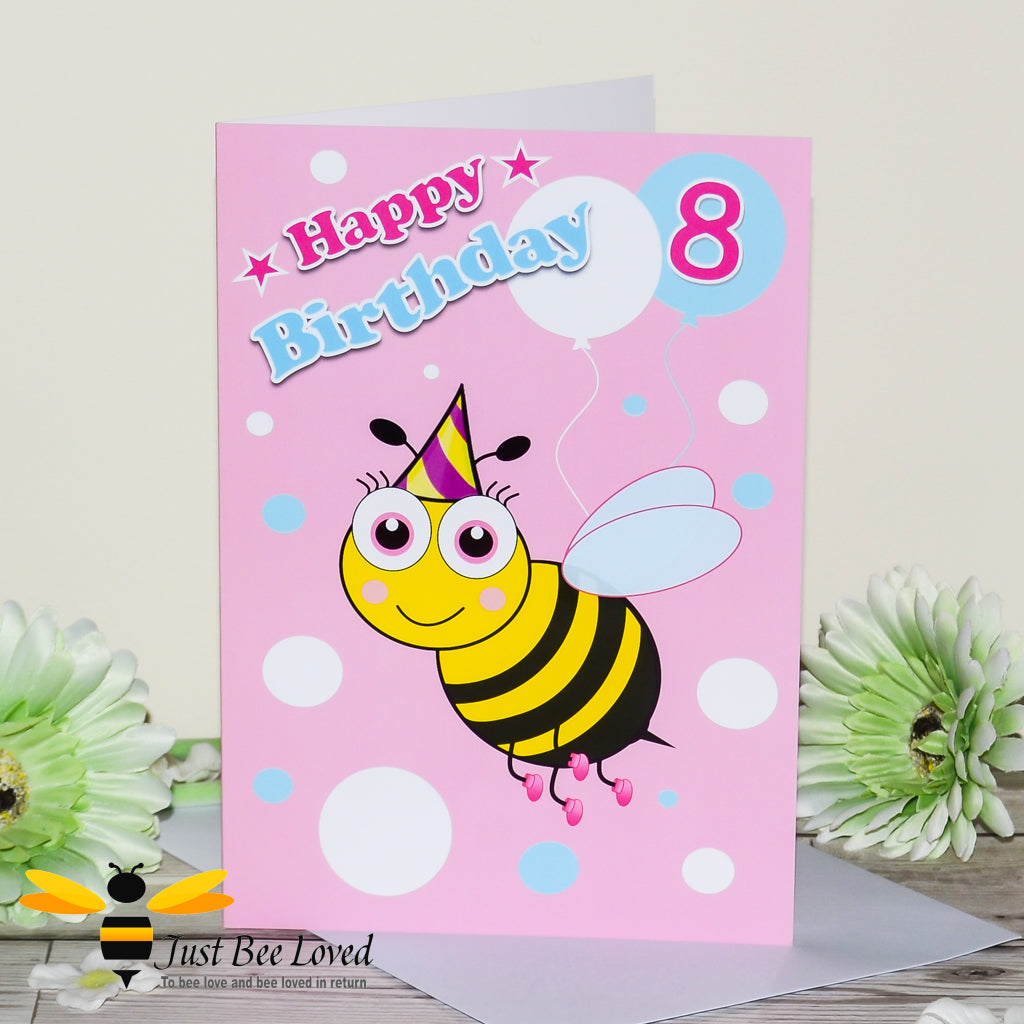a bee themed pink birthday card featuring a cartoon illustration of a bee holding a balloon with the number 8.