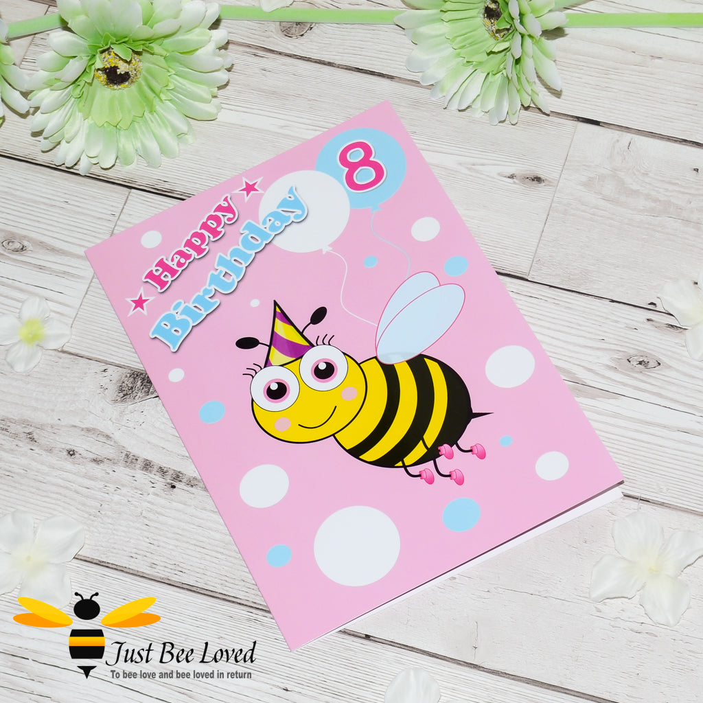 a bee themed pink with white and blue polka dots birthday card featuring a cartoon illustration of a bee holding a balloon with the number 8.