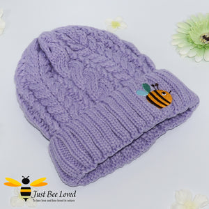 Aran style knitted hat featuring an embroidery bumblebee on front in purple colour