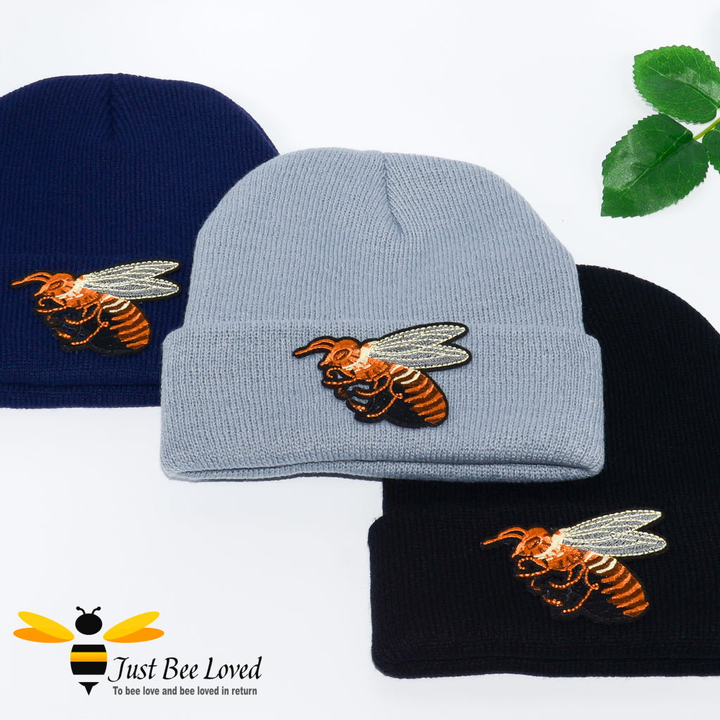 Ribbed knit beanie skull caps featuring a large front embroidered bee motif in blue, grey and black colours.