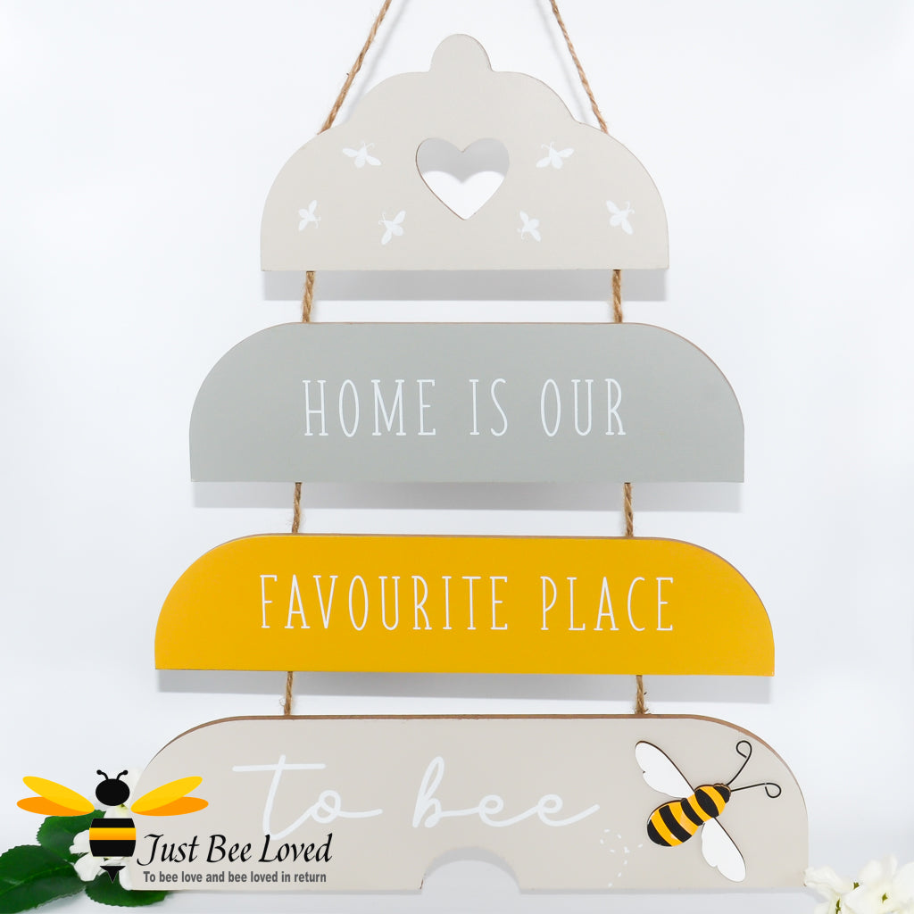 A wooden plaque with a three-dimensional beehive design and the text 'Home is our favourite place to bee'. 