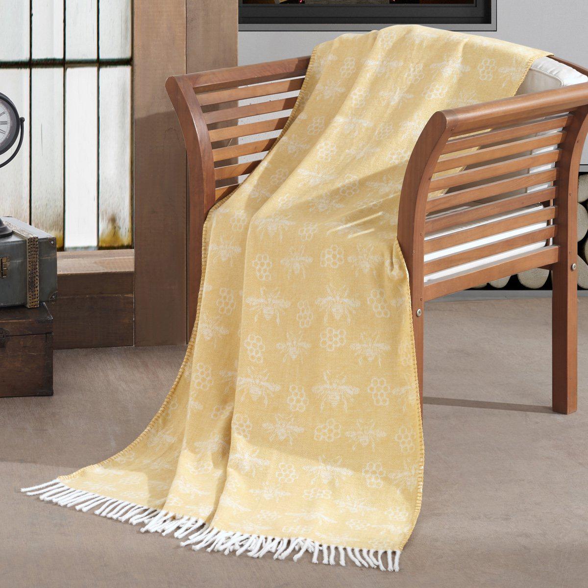 Woollen throw blanket in pastel yellow featuring an all over bee & honeycomb pattern with fringe border.