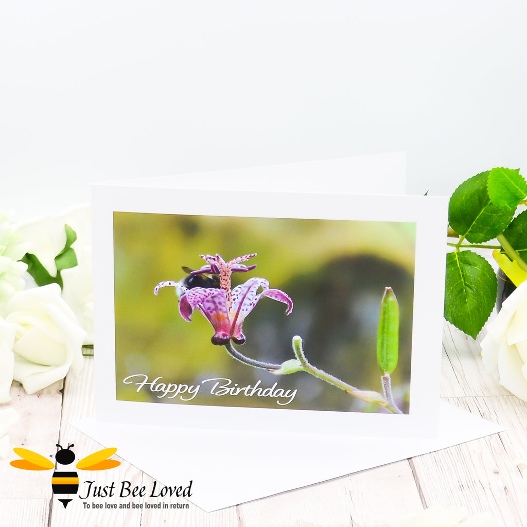 A happy birthday greeting bee card featuring an image of a bumblebee deep inside a flower cup.