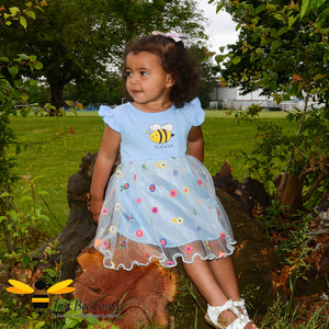 Two year old girl modelling blue lace bumblebee flower dress in park