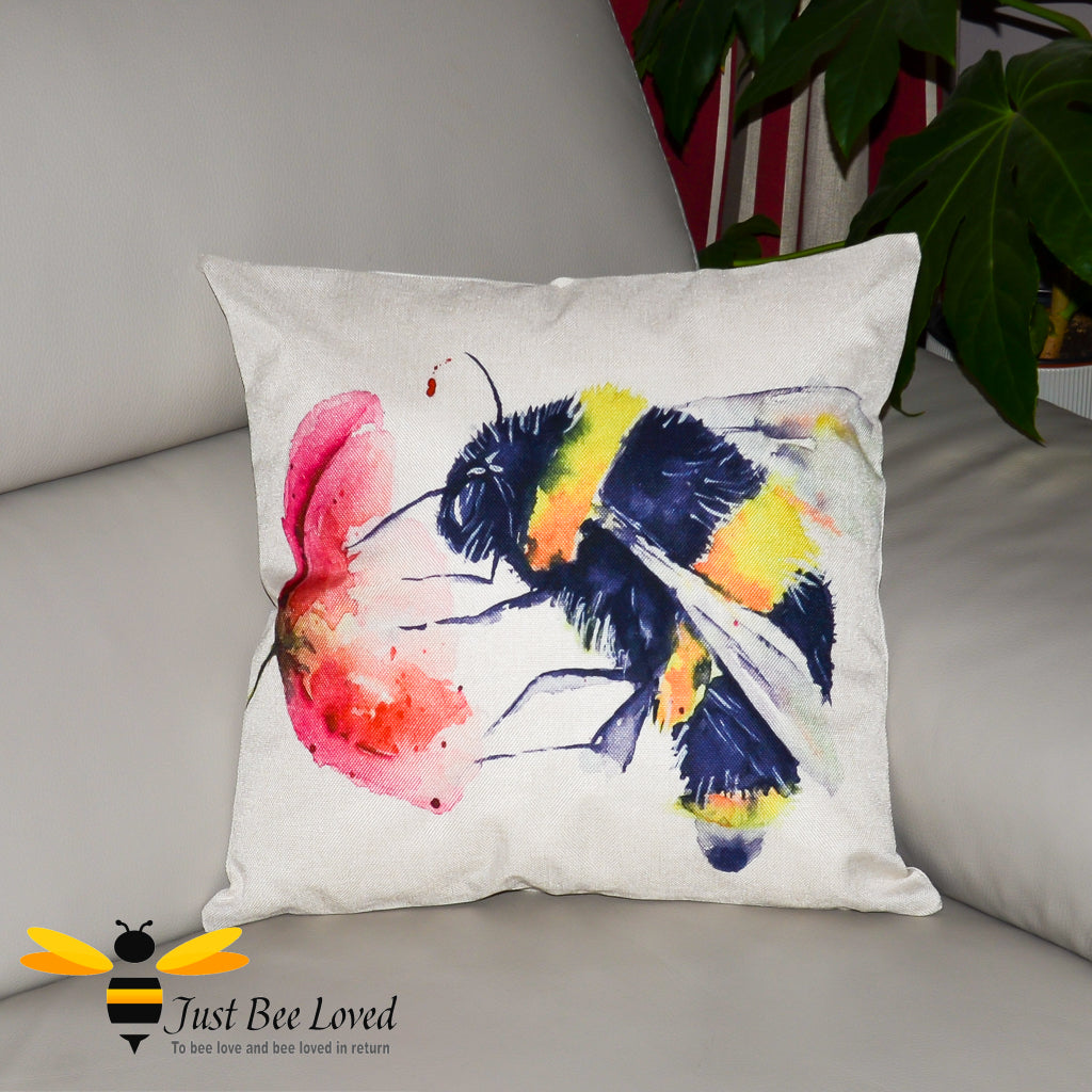 Cream cushion featuring a watercolour artwork design of a bumblebee foraging on wild poppy flower.