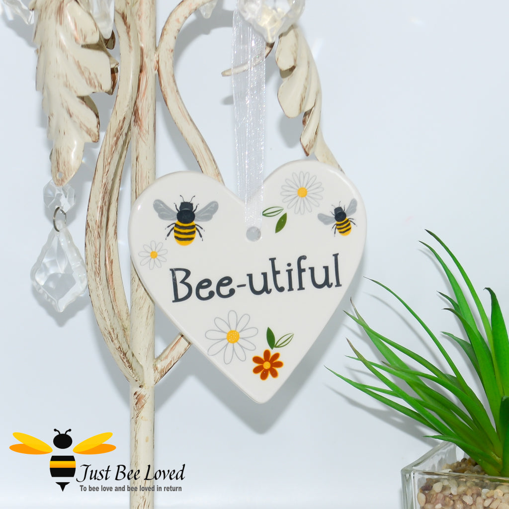 a ceramic hanging heart plaque decorated with bees and daisies and "beautiful" text.