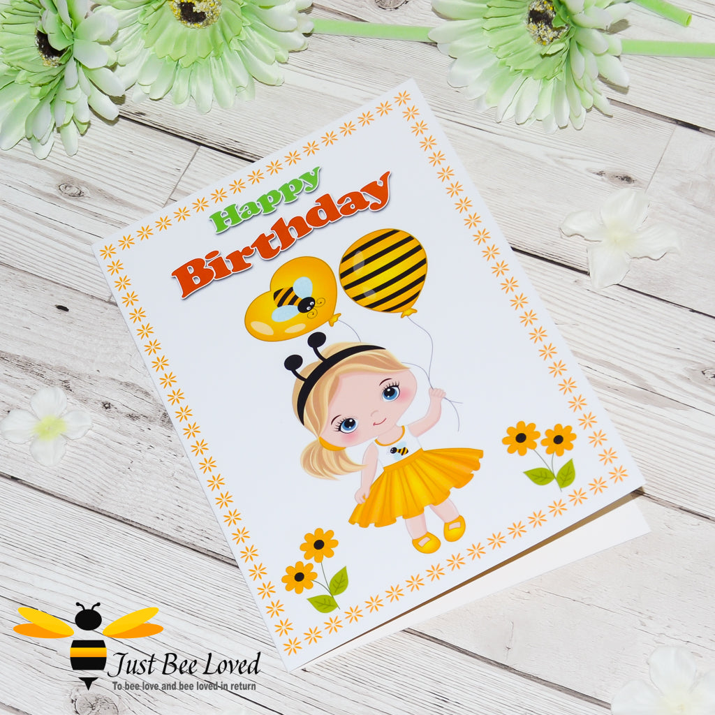 a birthday bee card featuring a cartoon illustration of a young girl wearing bee themed clothes and holding bee ballons, with daisy flowers.