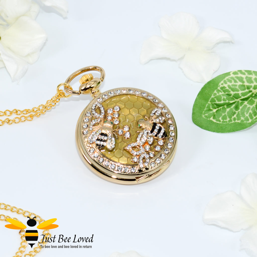 Gold coloured chained pocket watch with white crystal bees on honeycomb background