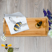 Load image into Gallery viewer, bamboo serving tray hand-painted by British artist Joanna Williams; featuring a painting of a bumblebee, with matching bee print cream cotton tea towel