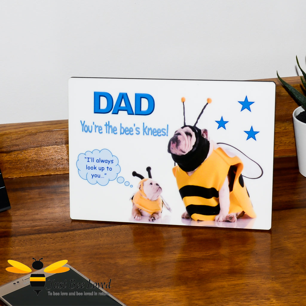 Wooden desk plaque with the text 'DAD You're the bee's knees!' and an illustration of a small bulldog wearing a bee costume looking up at a larger bulldog, which represents the dad.