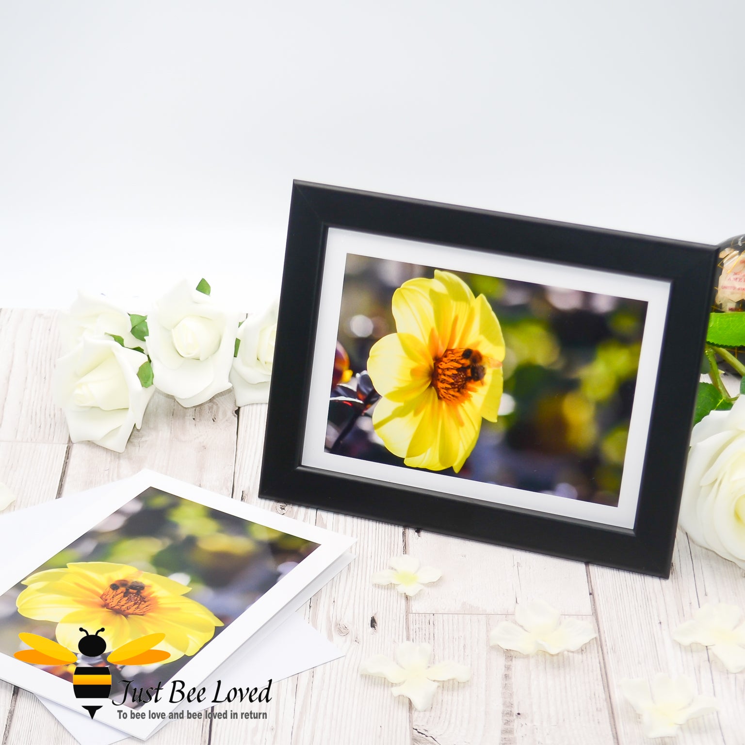 A framed greeting card depicting an image of a bee foraging on a sun kissed yellow dahlia flower against a blurred background.