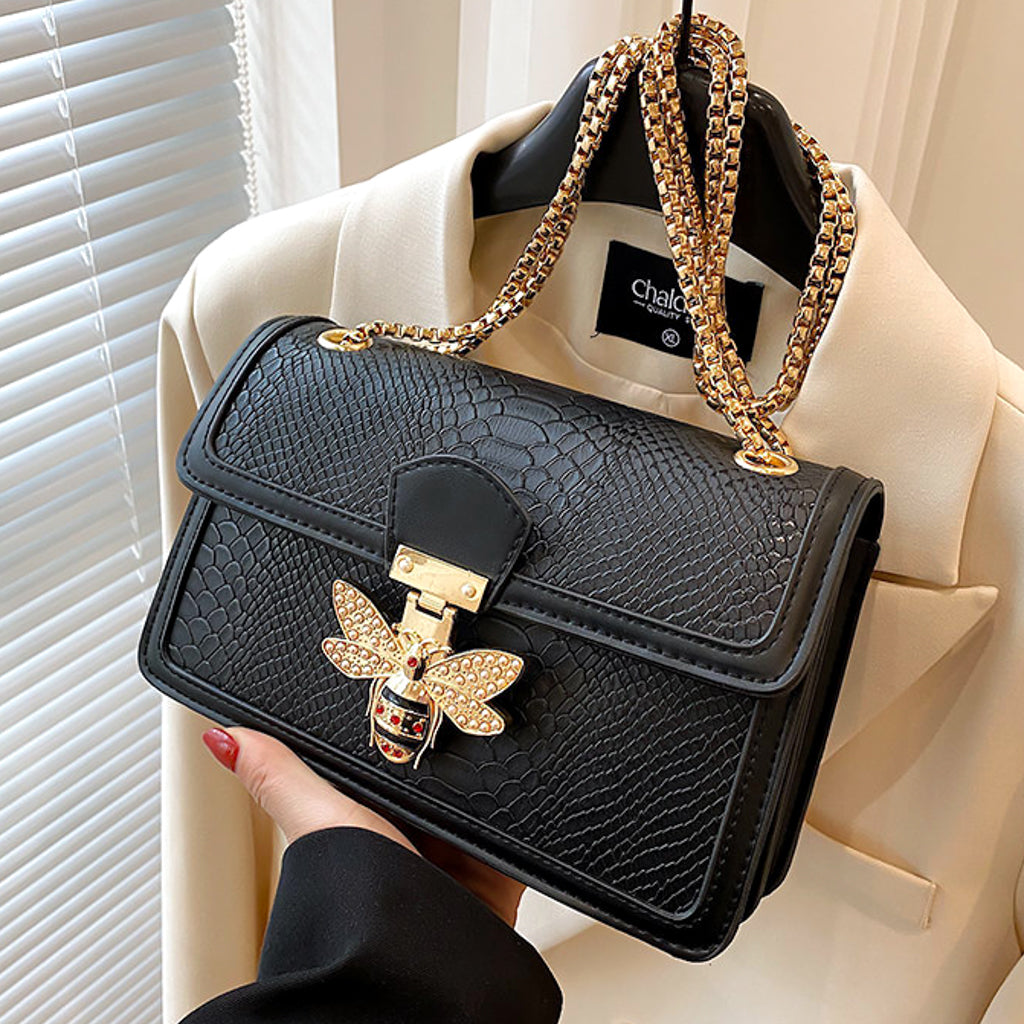 woman holding a Faux snake skin textured pu leather handbag with bee decoration in taupe colour