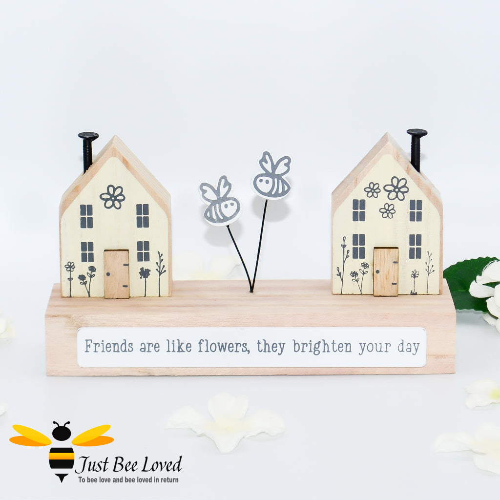 A wooden freestanding plaque featuring bees between two houses with "Friends are like flowers, they brighten your day" text.
