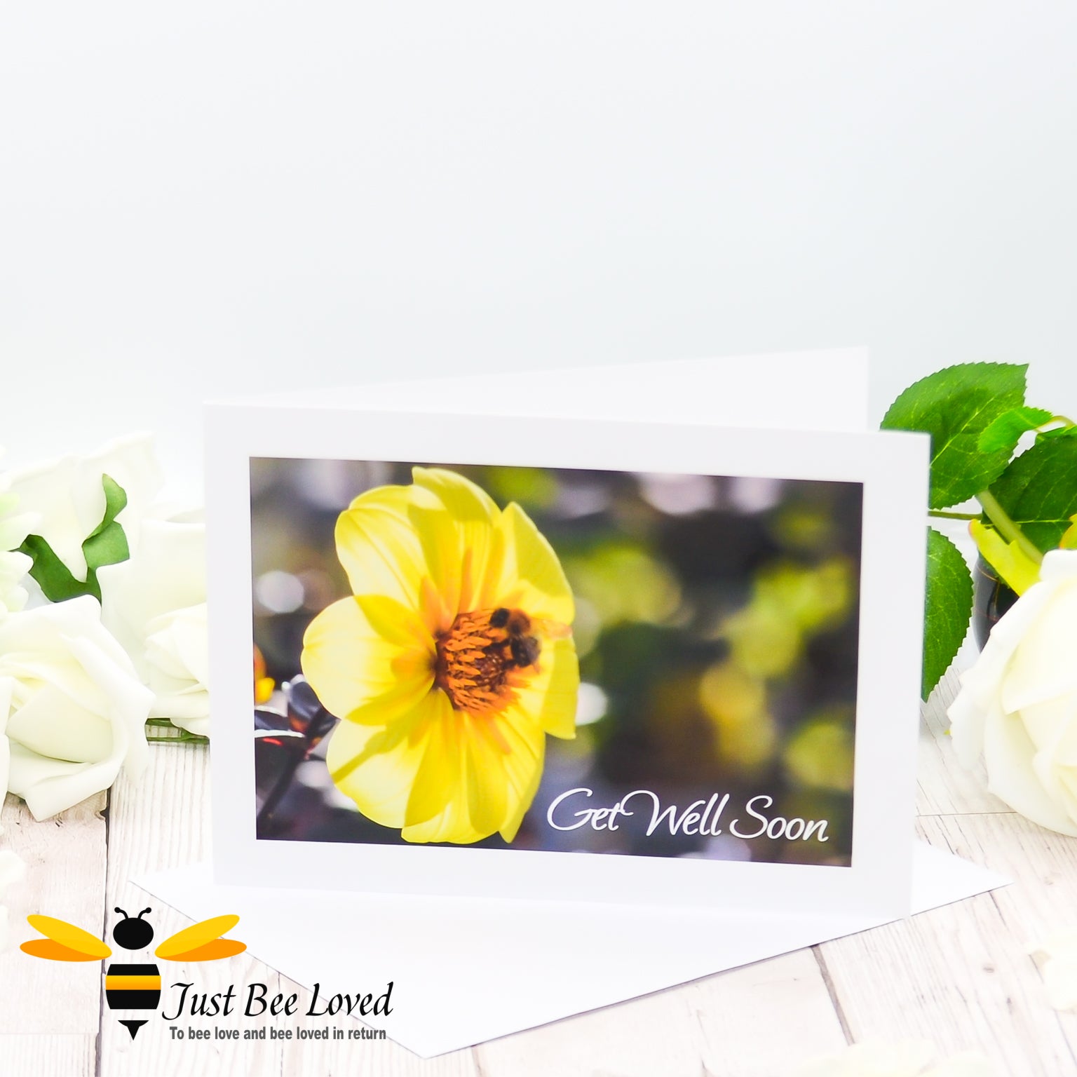 a greeting card depicting a bumblebee foraging on a yellow dahlia flower with 'get well soon' text.