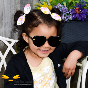 Little girl wearing black heart shaped bee sunglasses