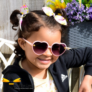 Little girl wearing pink heart shape bee sunglasses