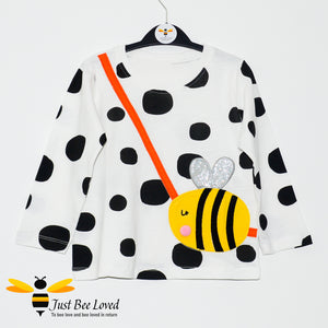 Girl's long sleeve white cotton top featuring multi-sized black polka dots with applique bumblebee handbag design