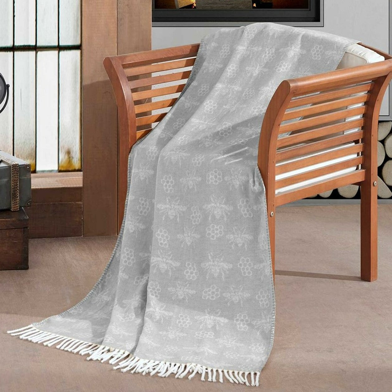 Woollen throw blanket in pastel grey featuring an all over bee & honeycomb pattern with fringe border.