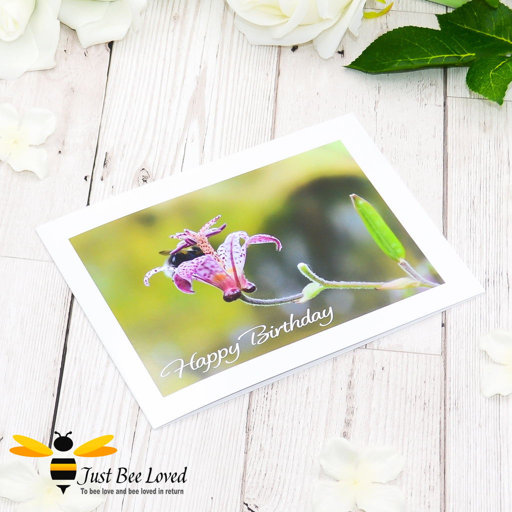 A happy birthday greeting bee card featuring an image of a bumblebee deep inside a flower cup.