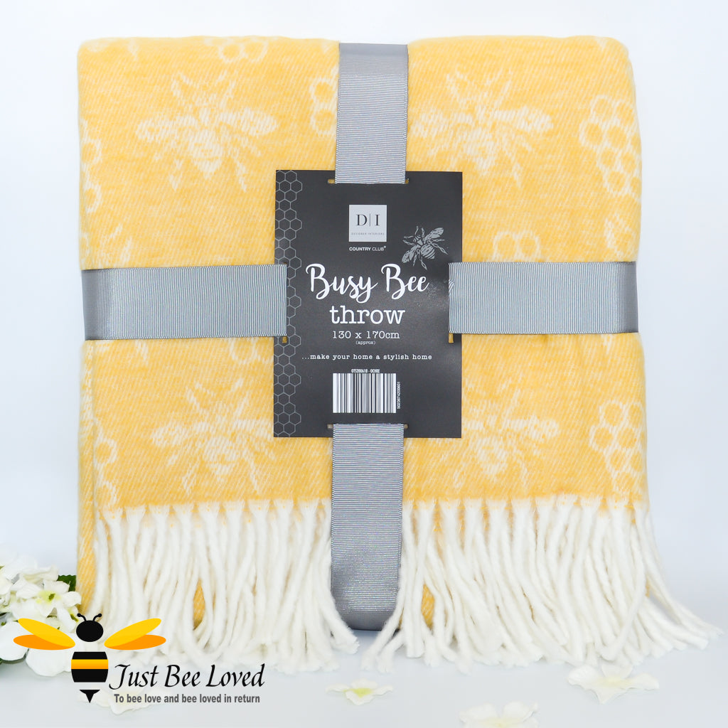 Woollen throw blanket in pastel yellow featuring an all over bee & honeycomb pattern with fringe border.