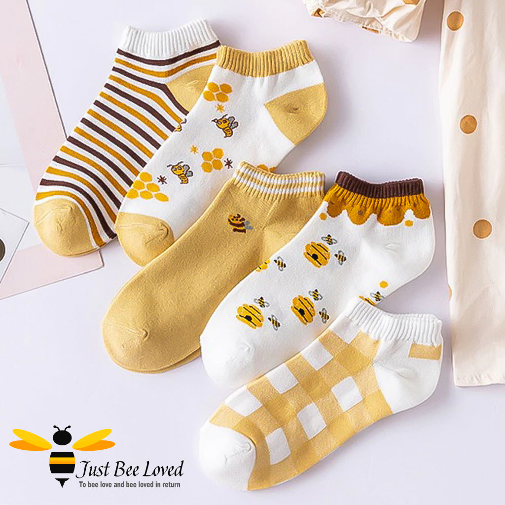 A collection of women's ankle socks with bee and honeycomb patterns, displayed in a variety of colours including white, yellow, and brown.