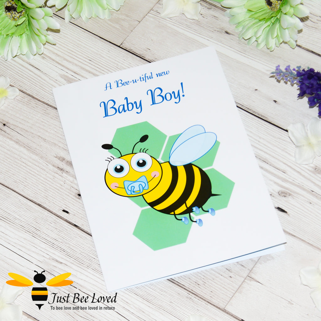 a newborn baby boy bee card featuring a cartoon illustration of a baby bee with a blue dummy and booties on a honeycomb background.