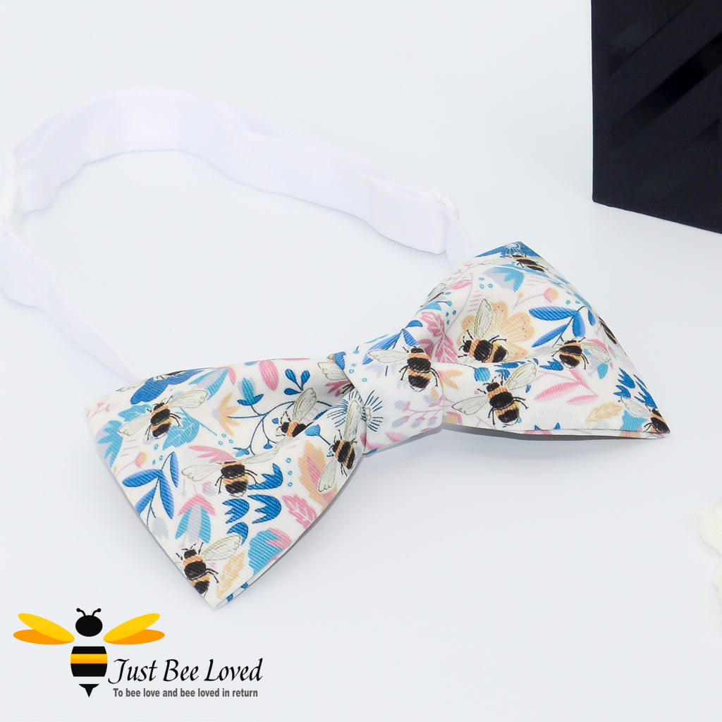 pre-tied white bow tie featuring an all over colourful print of bumblebees amongst a blue floral splash background