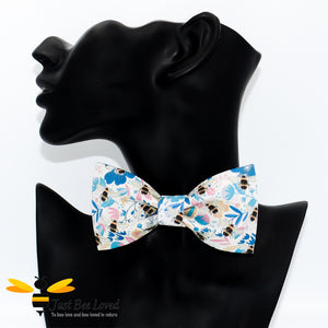 pre-tied white bow tie featuring an all over colourful print of bumblebees amongst a blue floral splash background